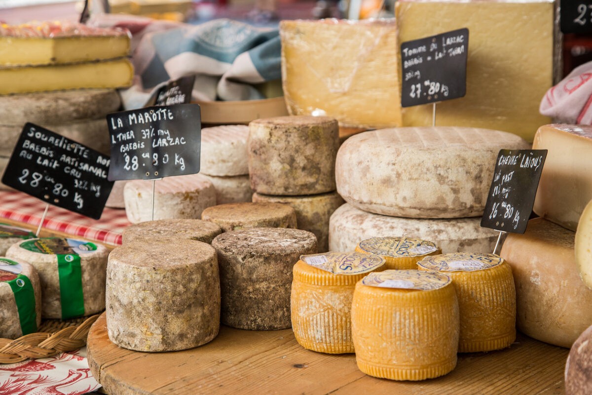 Photo captures assortment of cheeses on display at a typical french market.