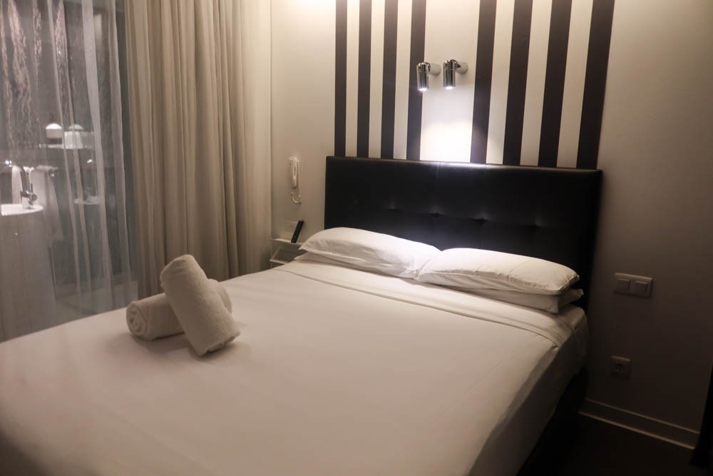 Bed with white sheets and two towels in the Acta Mimic Hotel in Barcelona
