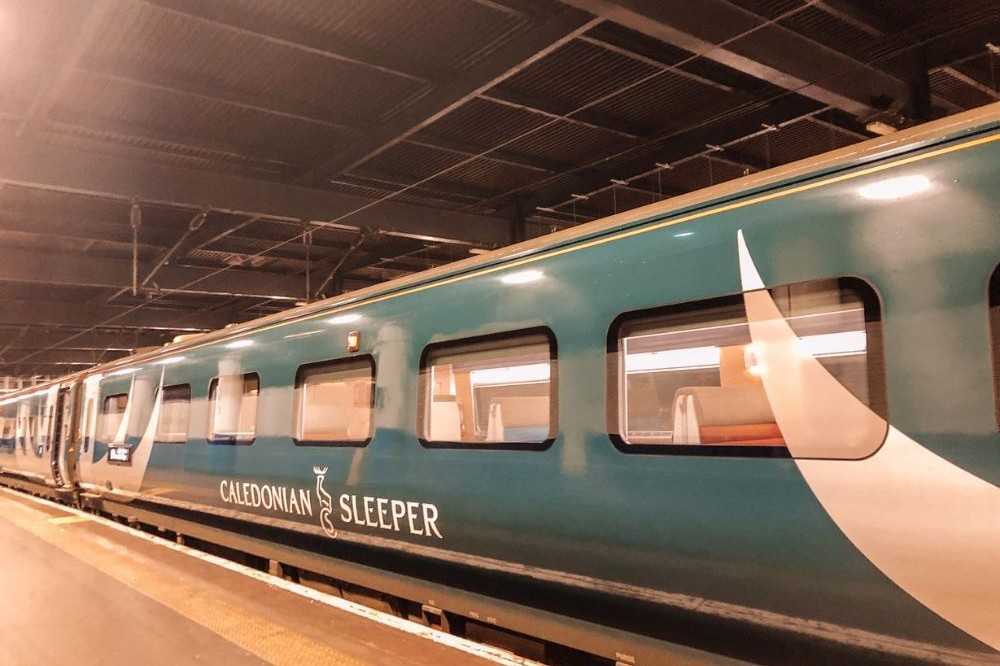 A shot of the blue Caledonian sleeper train sitting at a station.