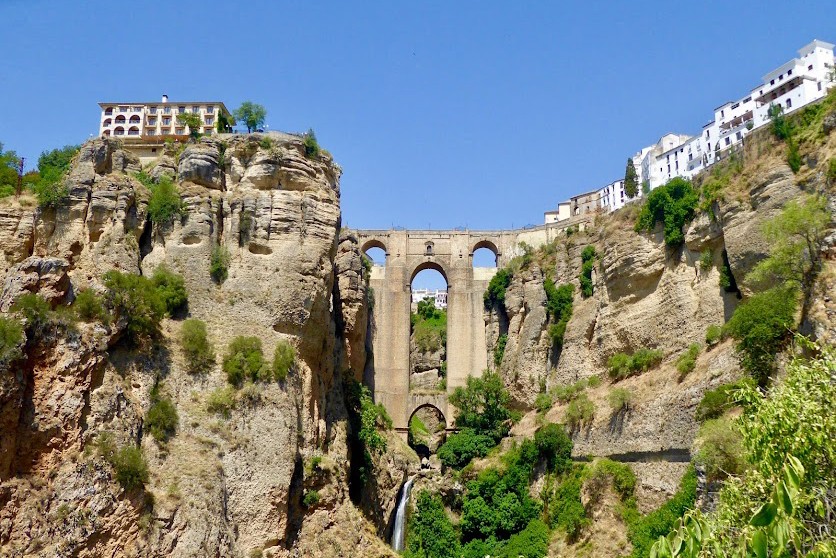 Beautiful views of the mountains and historic viaduct in Ronda, with blue skies and rocky scenery