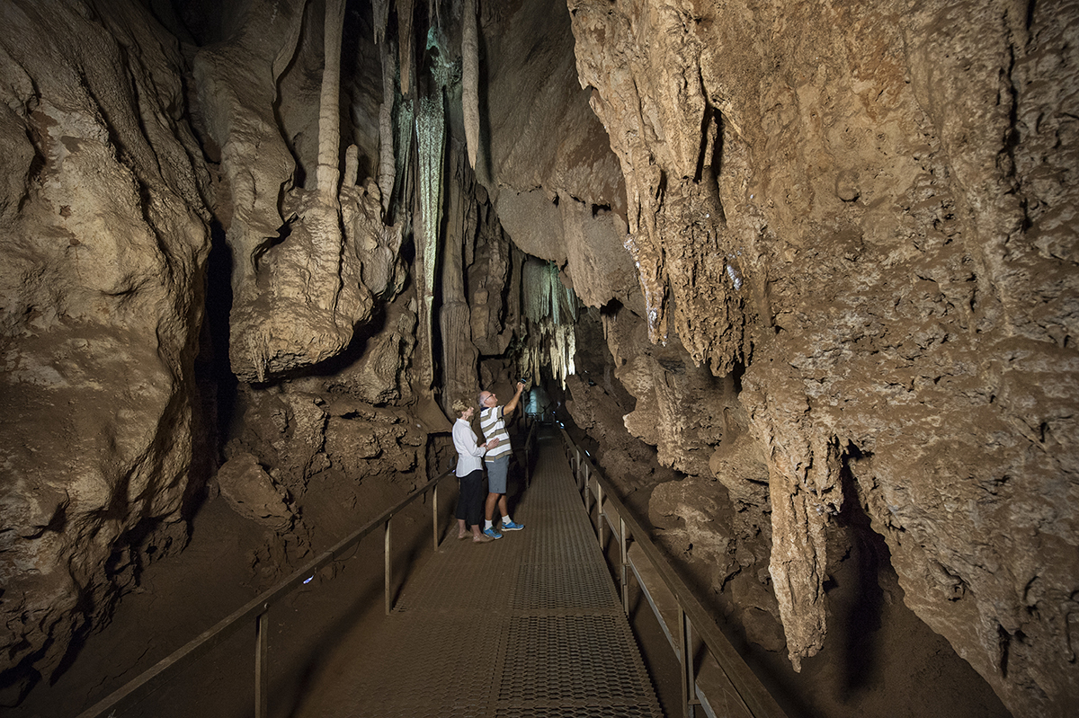Visitors explore the sparkling limestone formations of stalactites and stalagmites in the Cutta Cutta caves.<br srcset=
