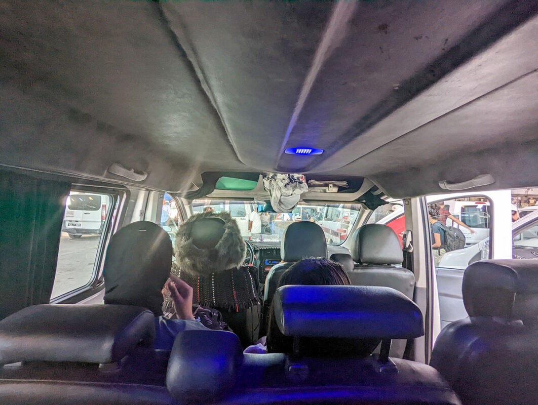 Inside a louage, with the back of three seats in the middle and the front row with the drivers seat
