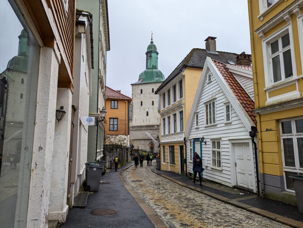 A cobbled street in downtown Bergen with a church at the end and a mishmash of buildings up the street