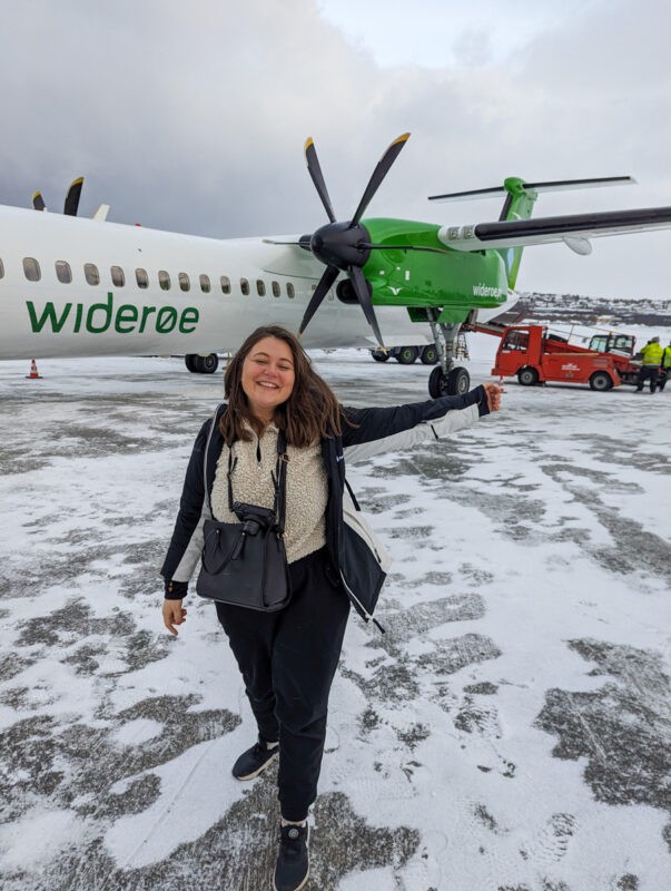 Claire standing in front of a Wideroe plane in Tromso, Norway