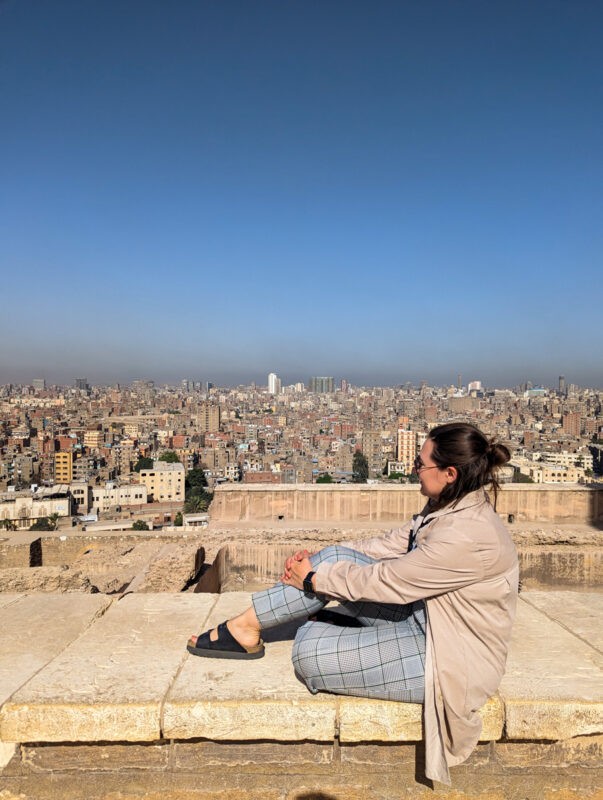 Claire sitting on the wall overlooking the dusty city of Cairo