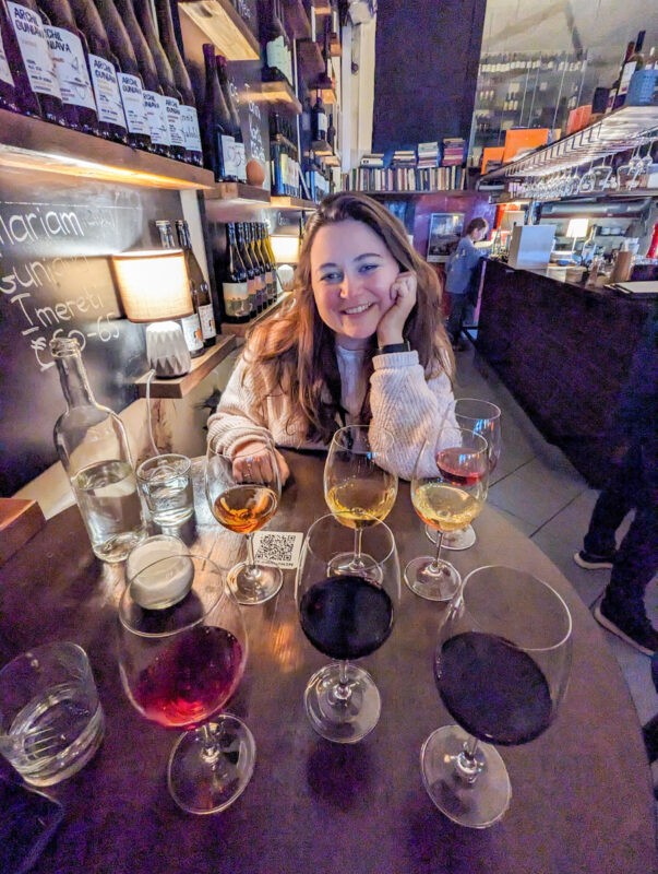 Girl sitting at a table with many glasses of wine in front of her