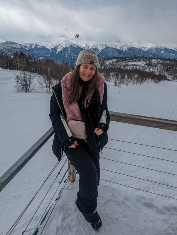 Girl standing at the top of a ski slope with mountains in background